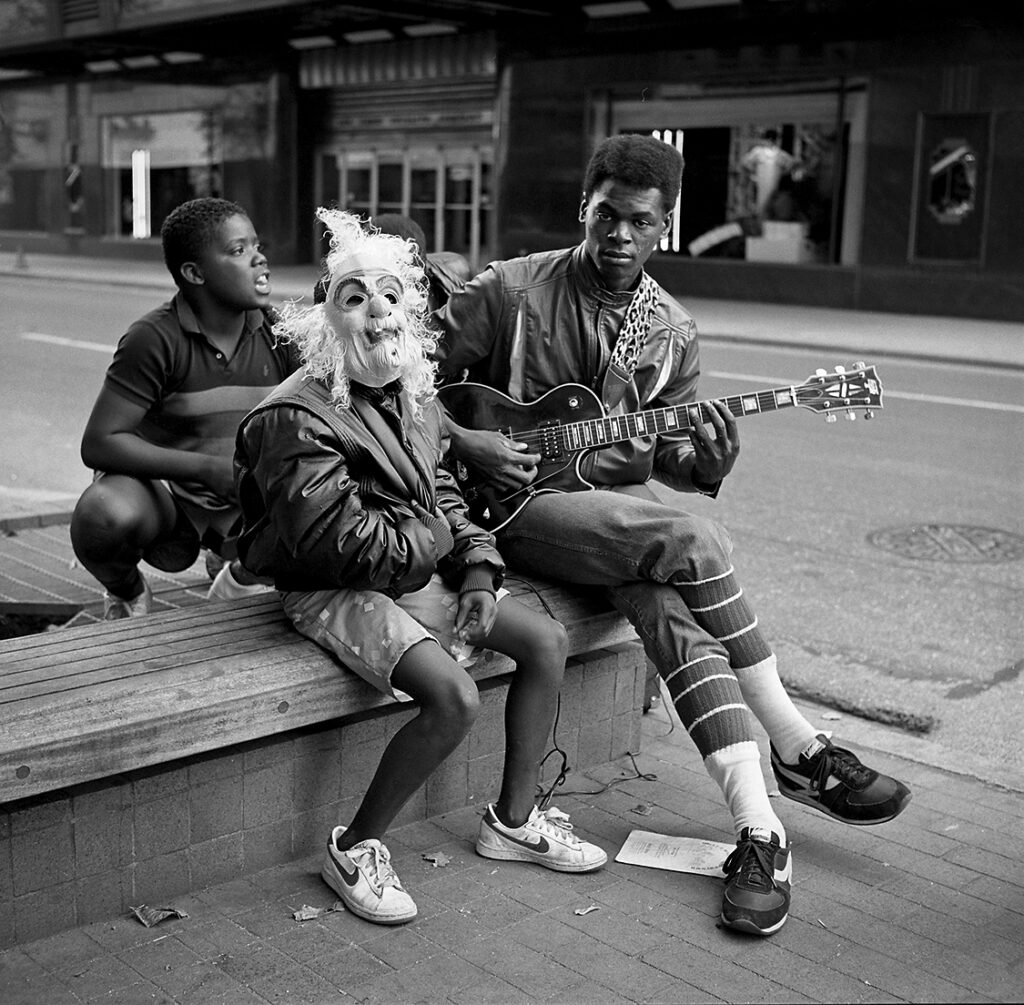 Michael Wilson, _Guitar Player with Friends, Race Street, Cincinnati, September 1985_, 1985. Gelatin silver print. Courtesy of the artist Eisele Waiting To Be Seen 2 Wilson Michael Guitar Player With Friends Race Street Cincinnati September 1985 Gelatin Silver Photograph, FotoFocus